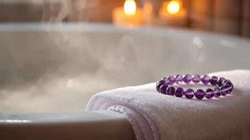 Amethyst jewelry bracelet placed on a white towel beside a warm steaming bath, symbolizing relaxation, clarity, and mindful crystal care.
