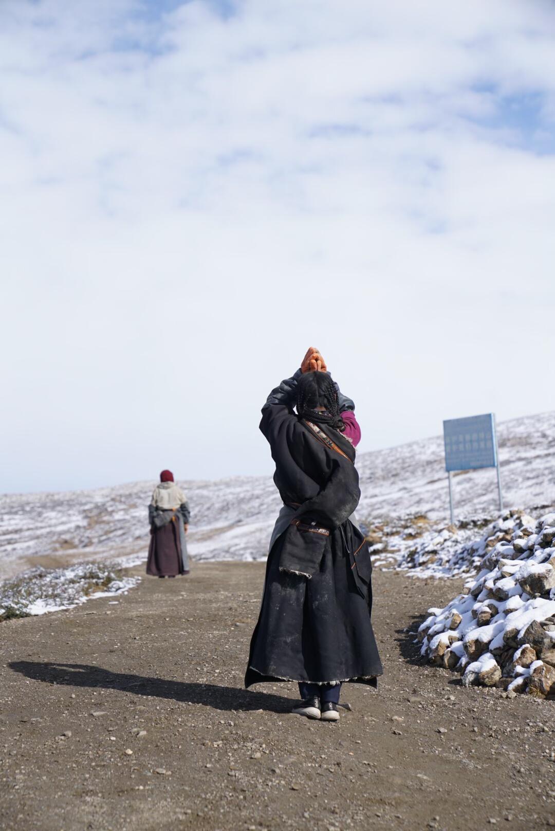 A Tibetan monk prays in the Himalayas near Mount Kailash, hands raised in devotion, embodying peace, faith, and spiritual discipline.