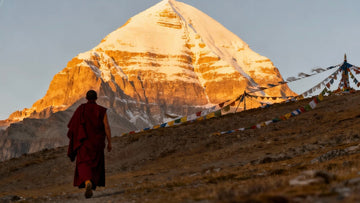 Tibetan monk walking toward Mount Kailash at sunrise with prayer flags in the wind, symbolizing devotion and spiritual pilgrimage.
